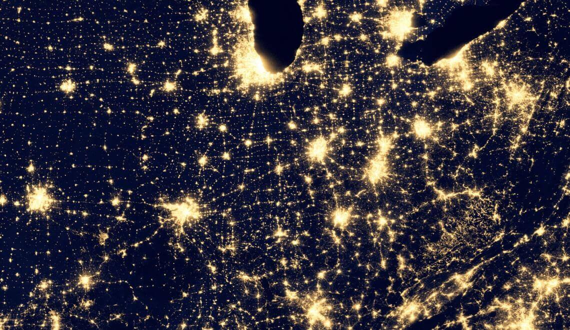 Satellite image of the United States at night showing lights of cities and roads